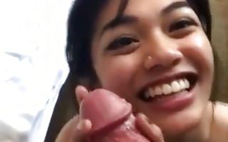 Asian cutie is blowing a giant dick and gives him a hand job